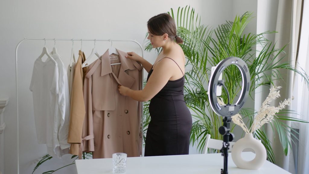 Woman in black dress arranging clothes on a rack for online selling with ring light.