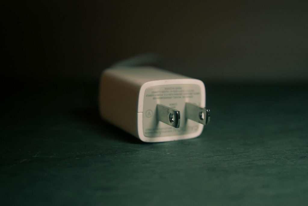 A focused view of a white wall charger plug lying on its side indoors.